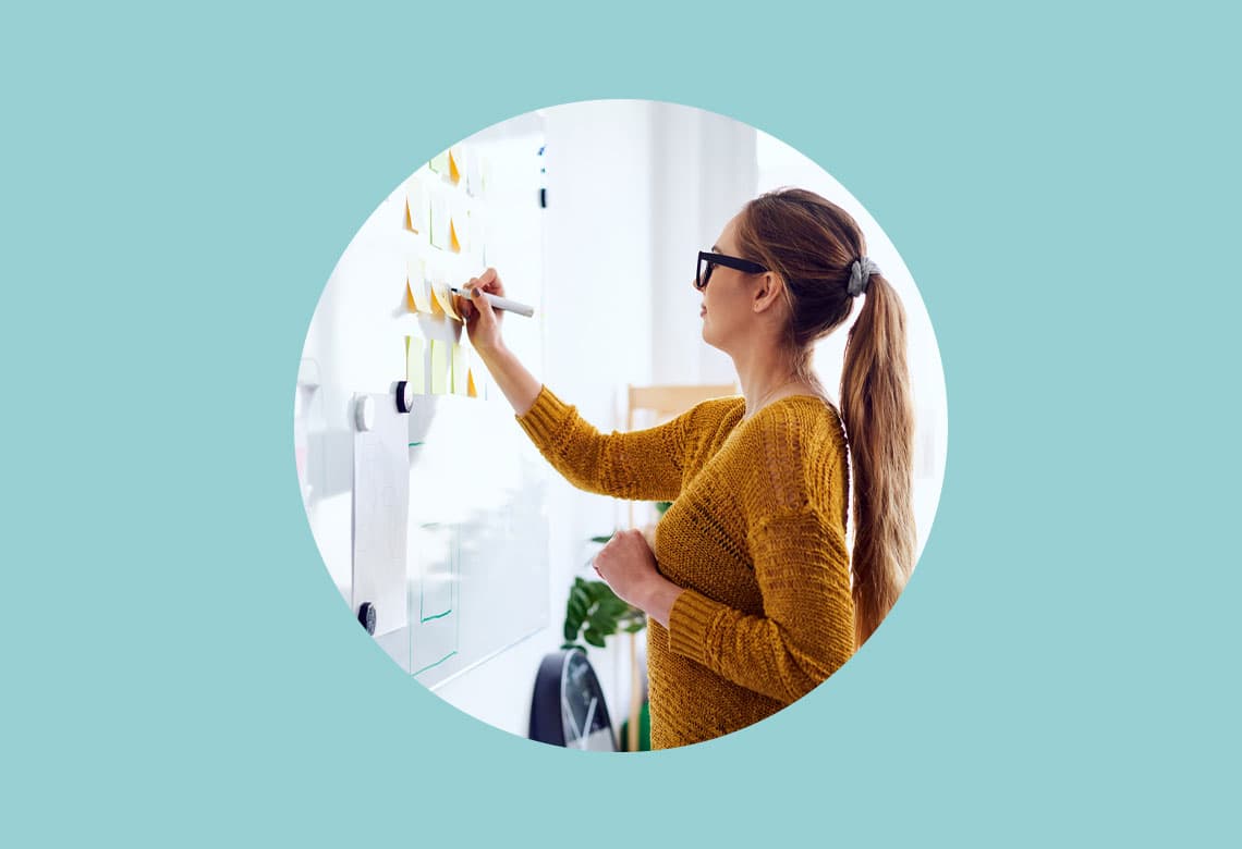 Young woman working in startup office writing on whiteboard